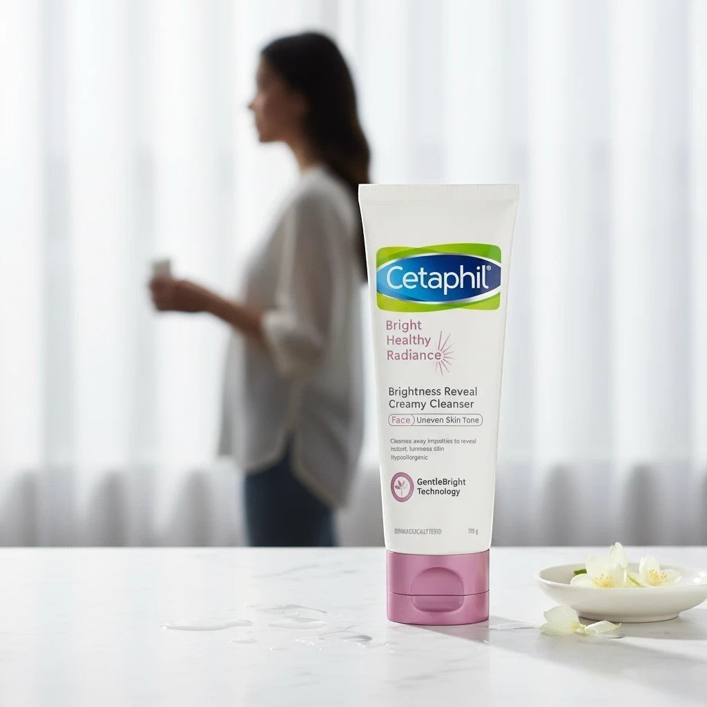 Tap2Own Cetaphil Bright Healthy Radiance creamy cleanser tube on a white surface with a woman in the blurred background.