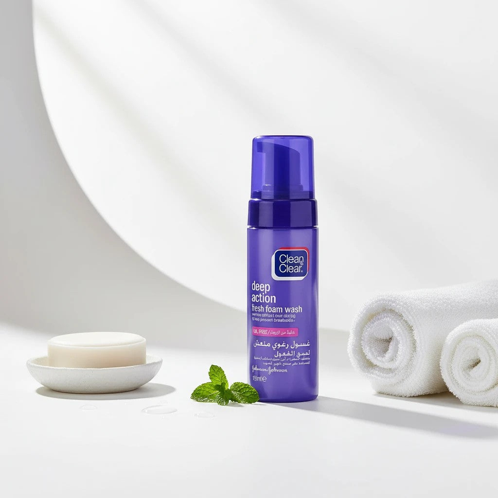 Tap2Own Clean & Clear Deep Action Fresh Foam facial cleanser in a purple bottle with a mint leaf and white towels.