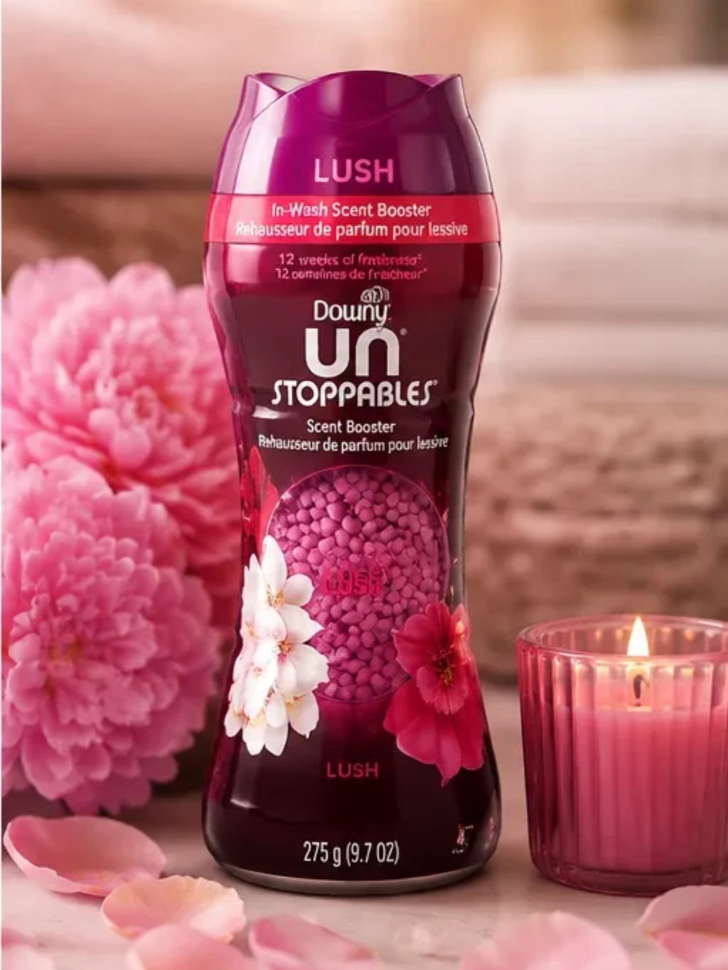 Tap2Own Downy Unstopables Lush in-wash scent booster bottle with pink floral accents and a lit candle nearby.