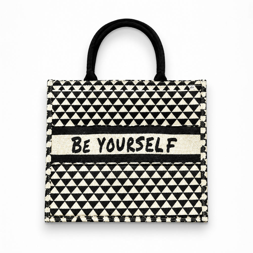 Tap2Own Be Yourself graphic tote bag in black and white geometric pattern with sturdy black handles.