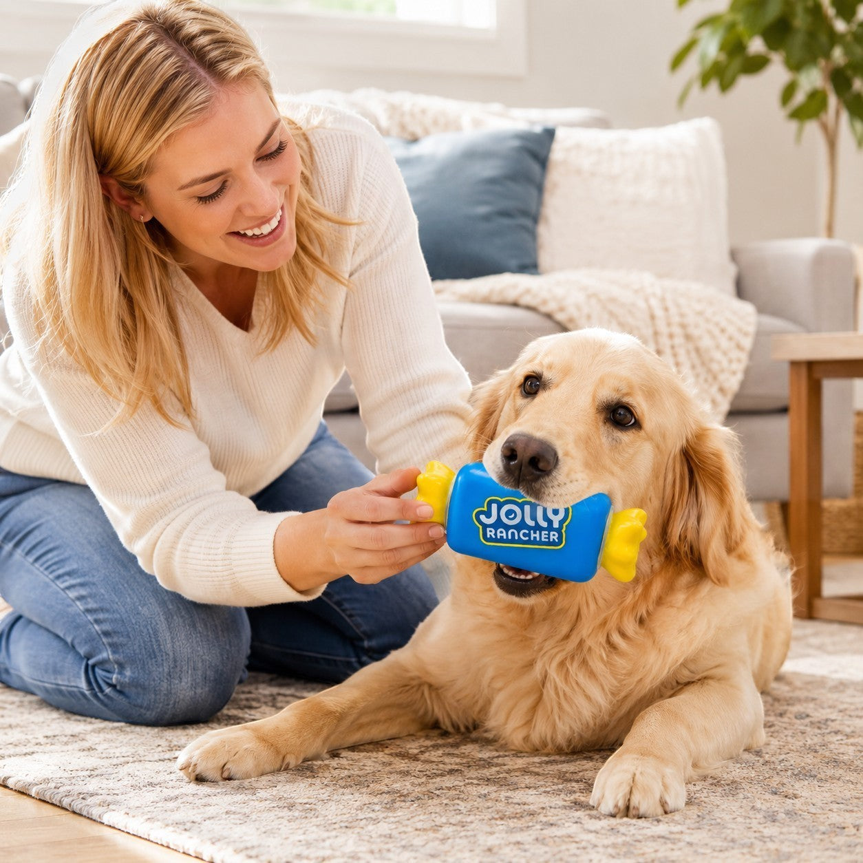 Tap2Own blue and yellow vinyl Jolly Rancher dog toy with squeaker, held by a woman playing with a golden retriever.