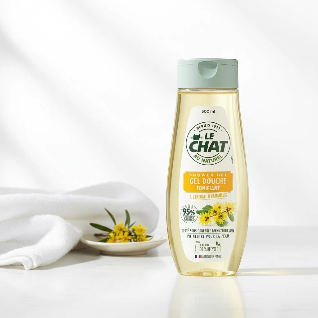 Tap2Own Le Chat Au Naturel Witch Hazel shower gel in a 300ml recycled plastic bottle on a white surface with a towel.