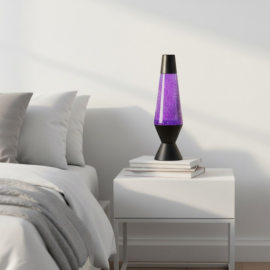 Tap2Own classic purple glitter lava lamp with black base and cap, on a nightstand next to a bed.