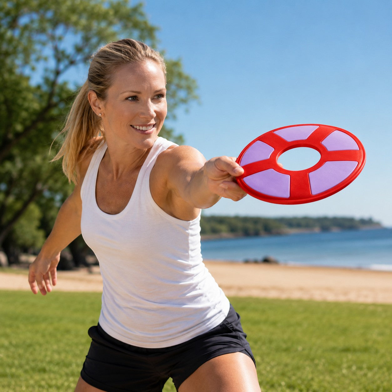 Tap2Own red and purple rubber flying ring dog toy held by a woman on a beach.