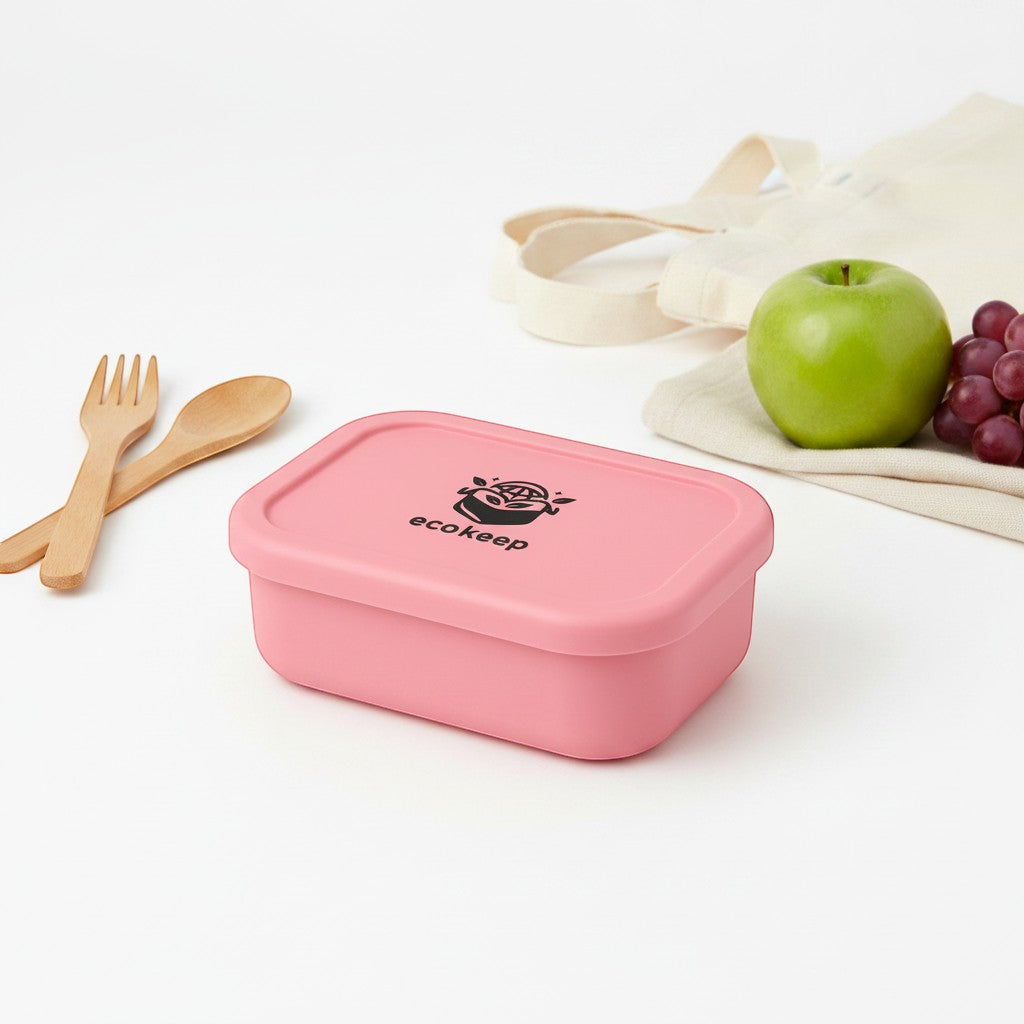 Tap2Own pink silicone bento lunch box with multiple compartments and secure lid. Includes wooden cutlery, apple, and grapes.
